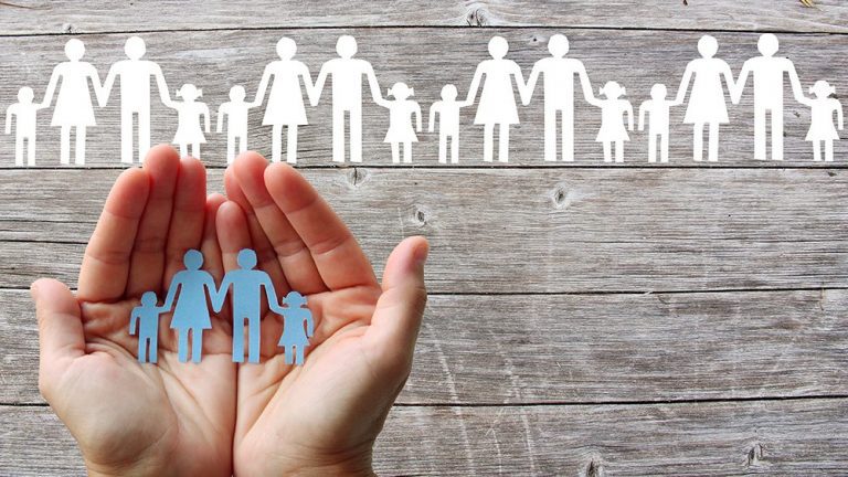 Paper family in hands on wooden background with white families