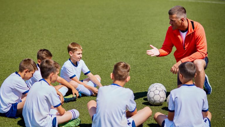 cropped-coach-instructing-football-team-in-field-2R8SJZB