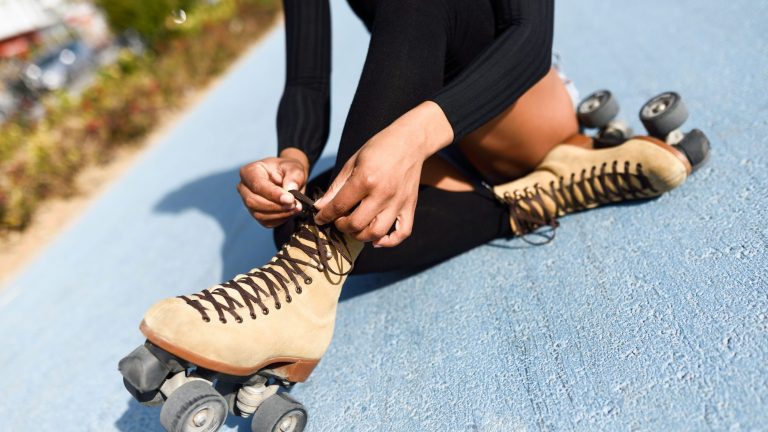 Unrecognizable black girl sitting on bike line and puts on skate